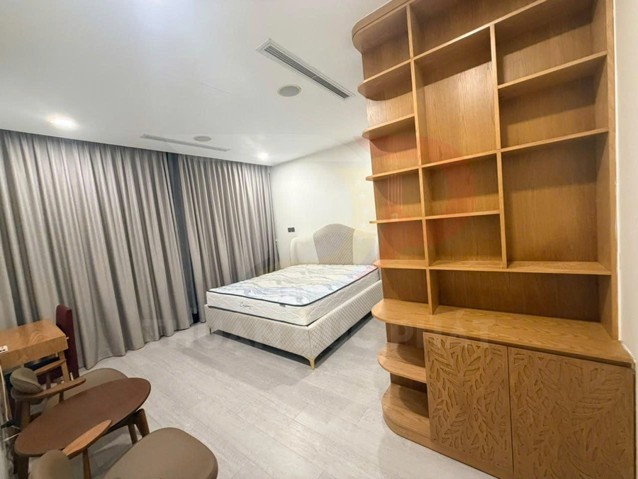 Phòng ngủ hiện đại với giường nệm đôi và kệ gỗ lớn nhiều ngăn cạnh bàn ghế gỗ nhỏ