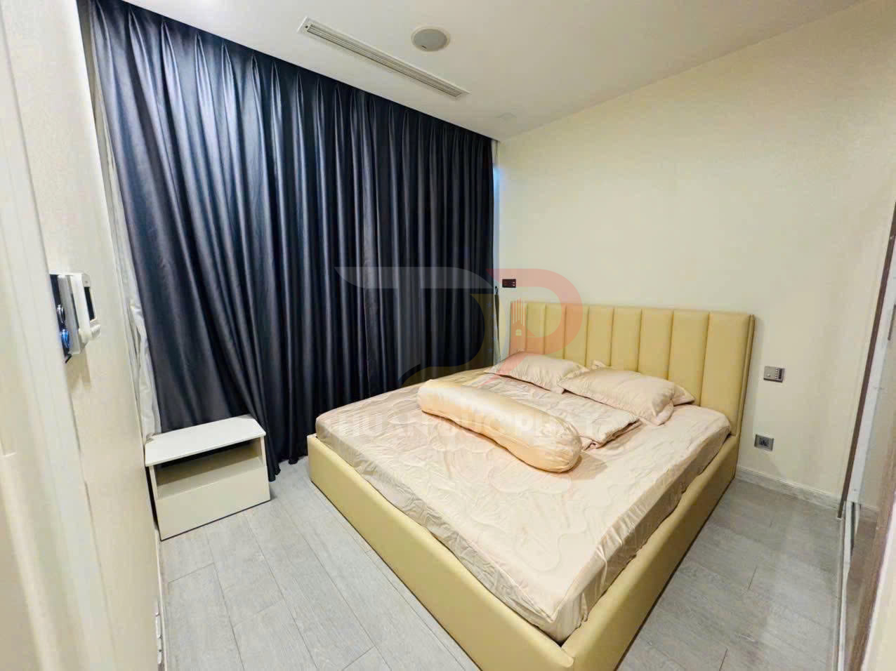 Phòng ngủ hiện đại với giường bọc da màu kem, chăn ga gối màu be và rèm tối màu