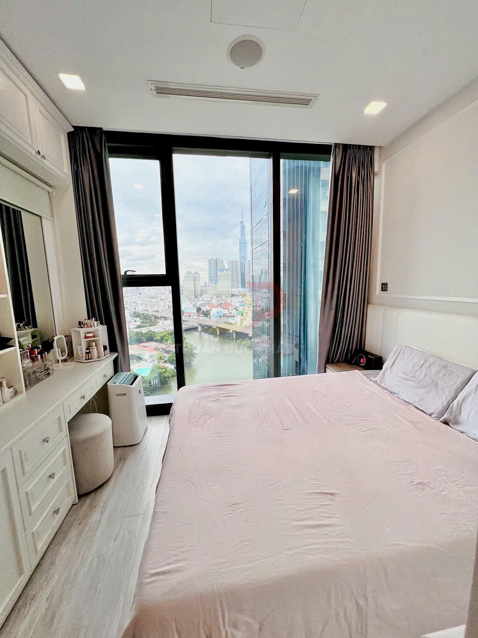 Phòng ngủ chung cư hiện đại với giường lớn cạnh cửa sổ kính toàn cảnh nhìn ra sông và thành phố