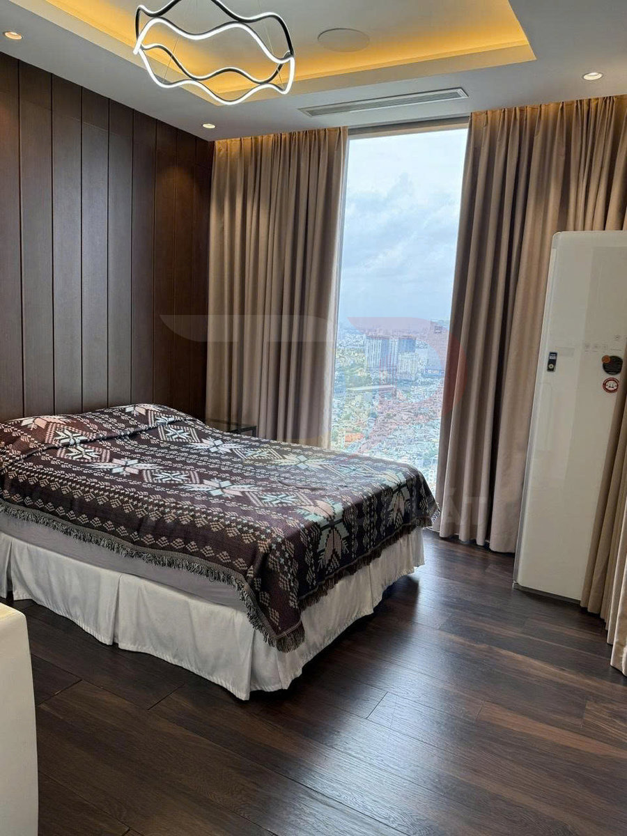 Phòng ngủ hiện đại với giường đôi trải chăn họa tiết, sàn gỗ và cửa sổ lớn nhìn ra thành phố