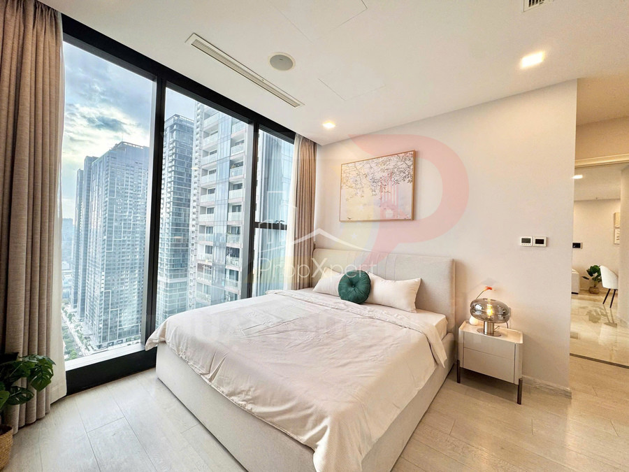 Phòng ngủ chung cư hiện đại với giường đôi trắng cạnh cửa sổ kính lớn nhìn ra các tòa nhà cao tầng