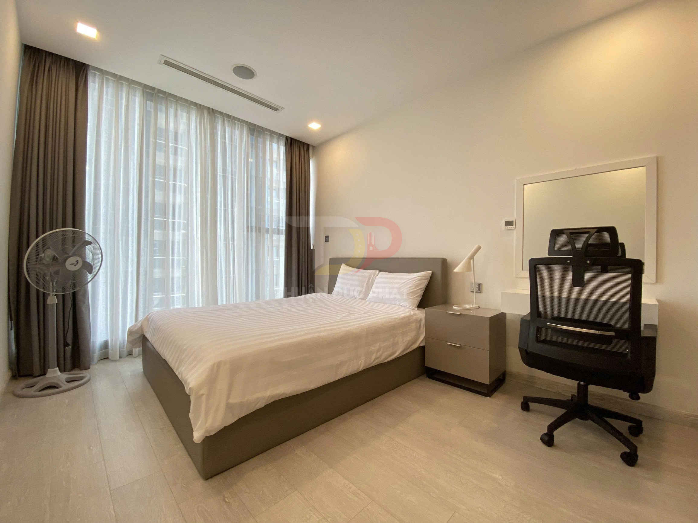 Phòng ngủ hiện đại với giường đôi ga trắng, bàn làm việc và ghế xoay cạnh cửa sổ lớn có rèm