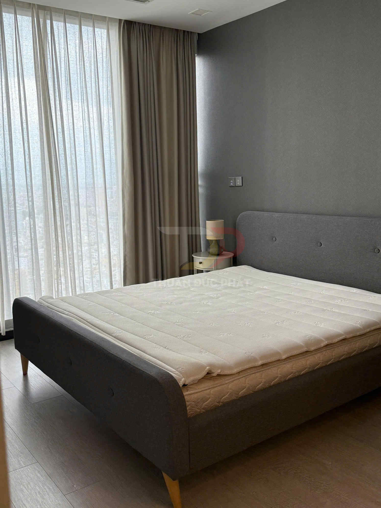 Giường ngủ bọc nệm màu xám hiện đại với nệm trắng trong phòng ngủ có rèm cửa sổ lớn