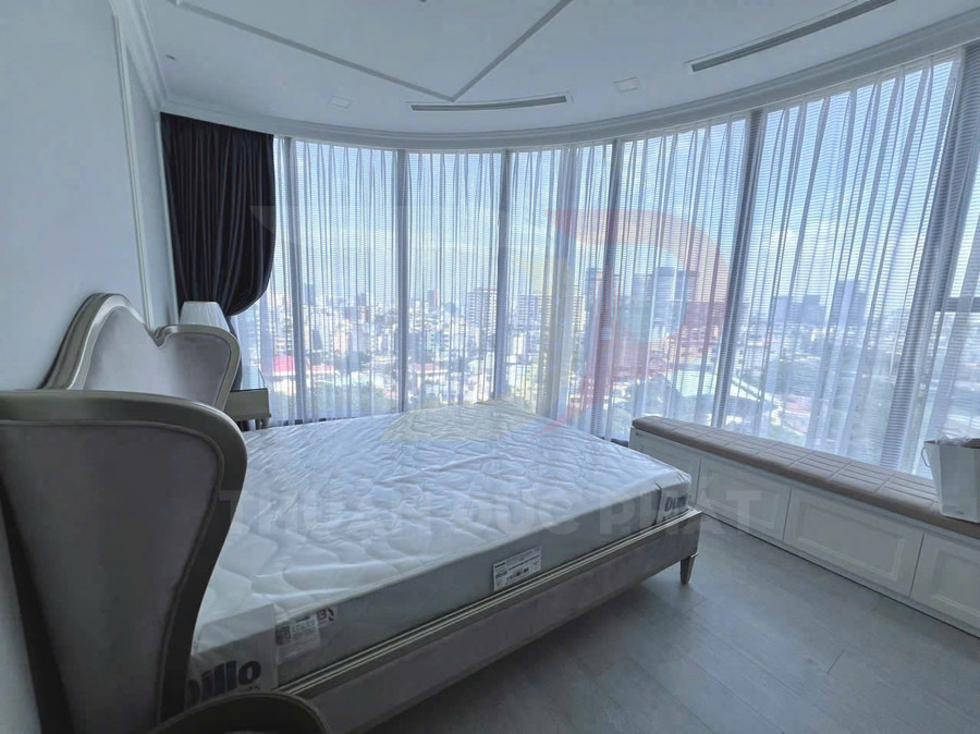 Giường ngủ hiện đại với nệm trắng cạnh cửa kính lớn nhìn ra thành phố sáng tự nhiên