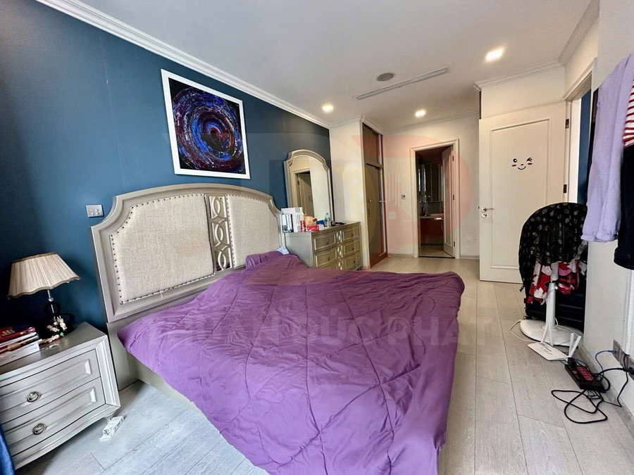 Phòng ngủ hiện đại với giường lớn chăn tím, tủ đầu giường và bàn trang điểm gương lớn