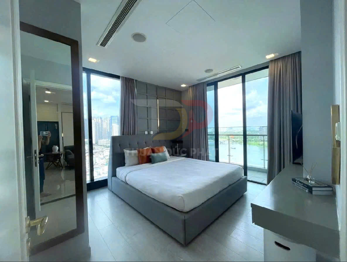 Phòng ngủ căn hộ hiện đại với giường đôi lớn, cửa kính toàn cảnh nhìn ra sông và nội thất tối giản