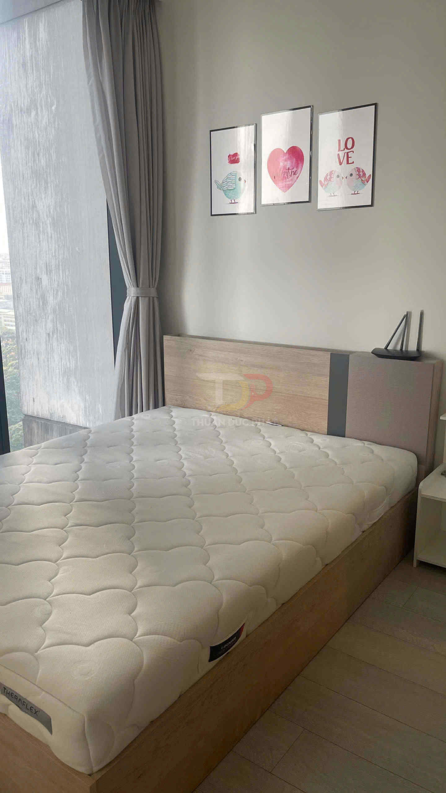 Nệm TheraFlex màu trắng trên giường gỗ trong phòng ngủ sáng với tranh treo tường trang trí