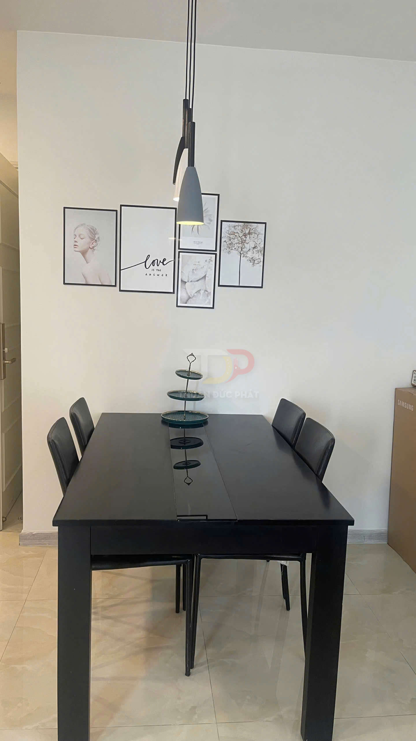 Bộ bàn ăn gỗ màu đen kèm bốn ghế da đen trong phòng ăn hiện đại treo đèn thả và tranh trang trí tường