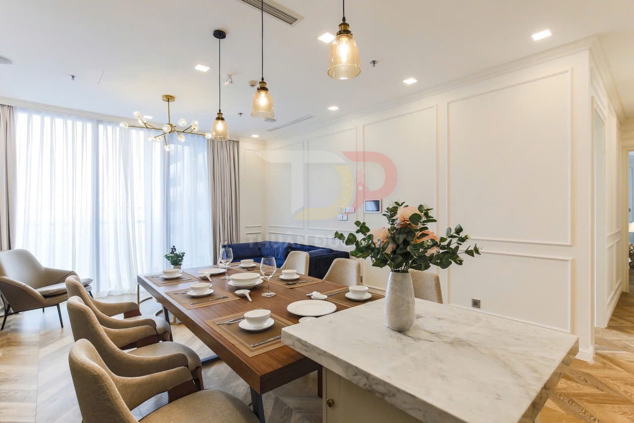 Bàn ăn gỗ hiện đại bày biện bát đĩa ly rượu trong phòng khách chung cư sang trọng ánh sáng tự nhiên