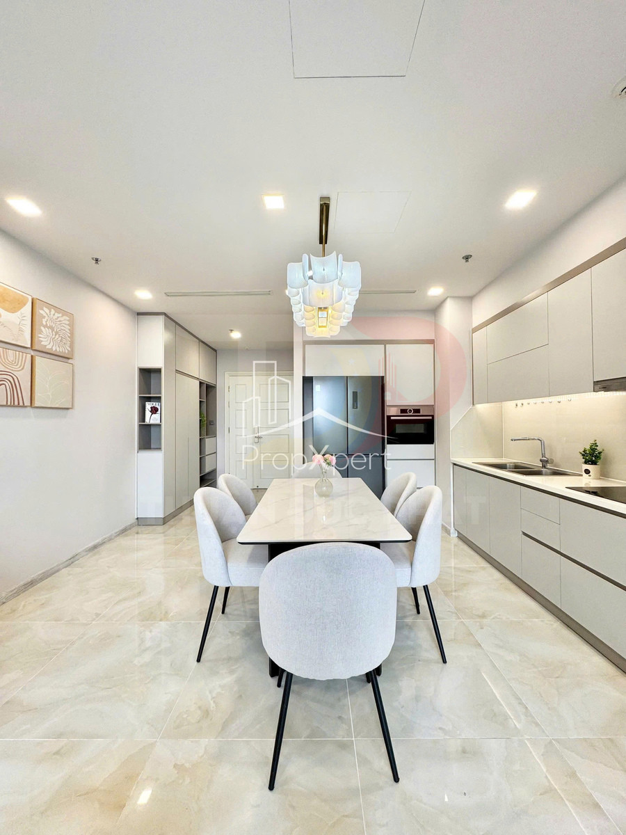 Bàn ăn mặt đá với sáu ghế bọc nỉ trong căn bếp hiện đại tông trắng sáng