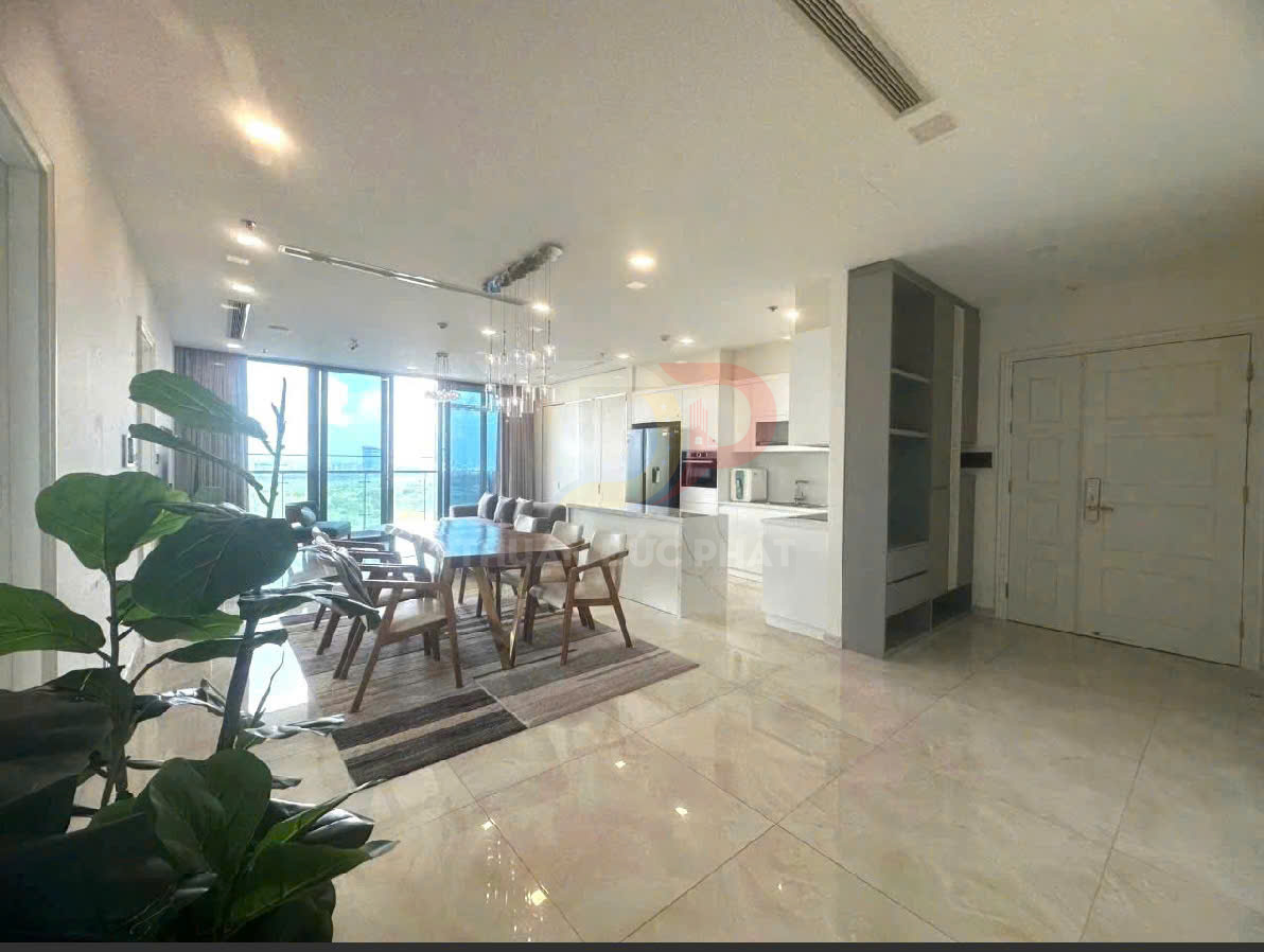 Phòng khách và bếp căn hộ hiện đại với bàn ăn gỗ, ghế nệm và cửa kính lớn nhìn ra ban công