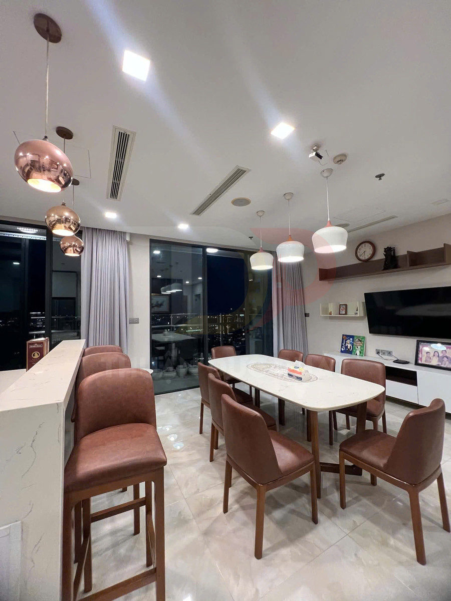 Bộ bàn ăn mặt đá với ghế da nâu trong phòng ăn chung cư hiện đại, đèn thả trang trí trên trần