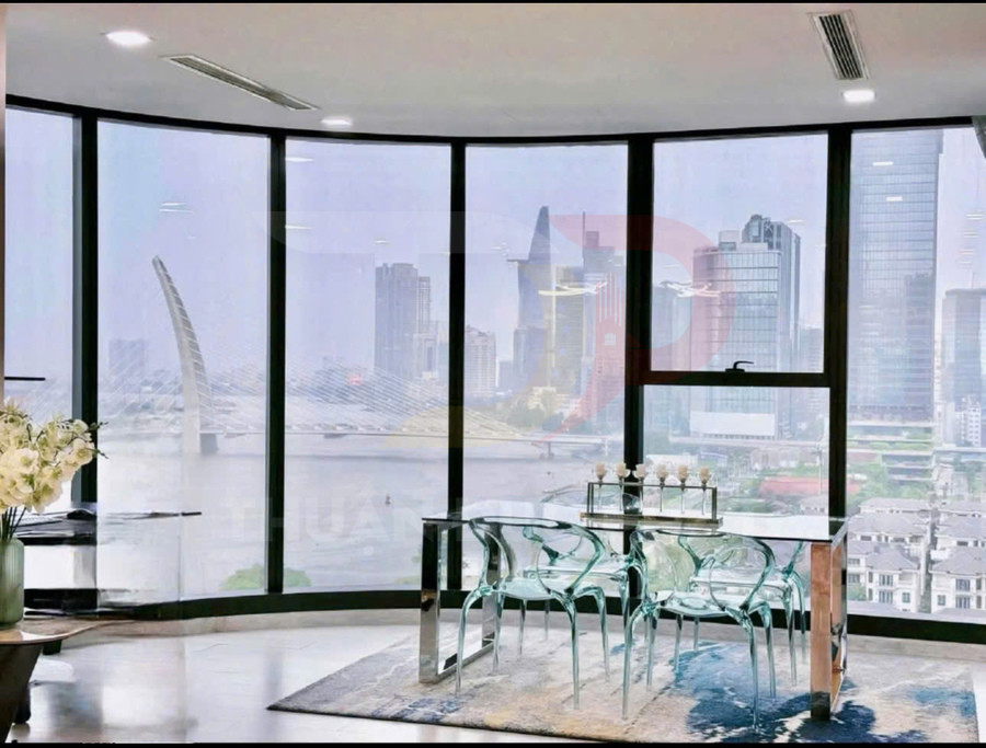 Bàn ăn kính hiện đại với ghế trong suốt đặt cạnh cửa kính lớn nhìn ra thành phố và sông