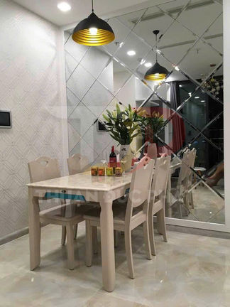 Bộ bàn ăn gỗ 4 ghế màu kem đặt cạnh tường gương, trang trí lọ hoa và đèn thả trần hiện đại