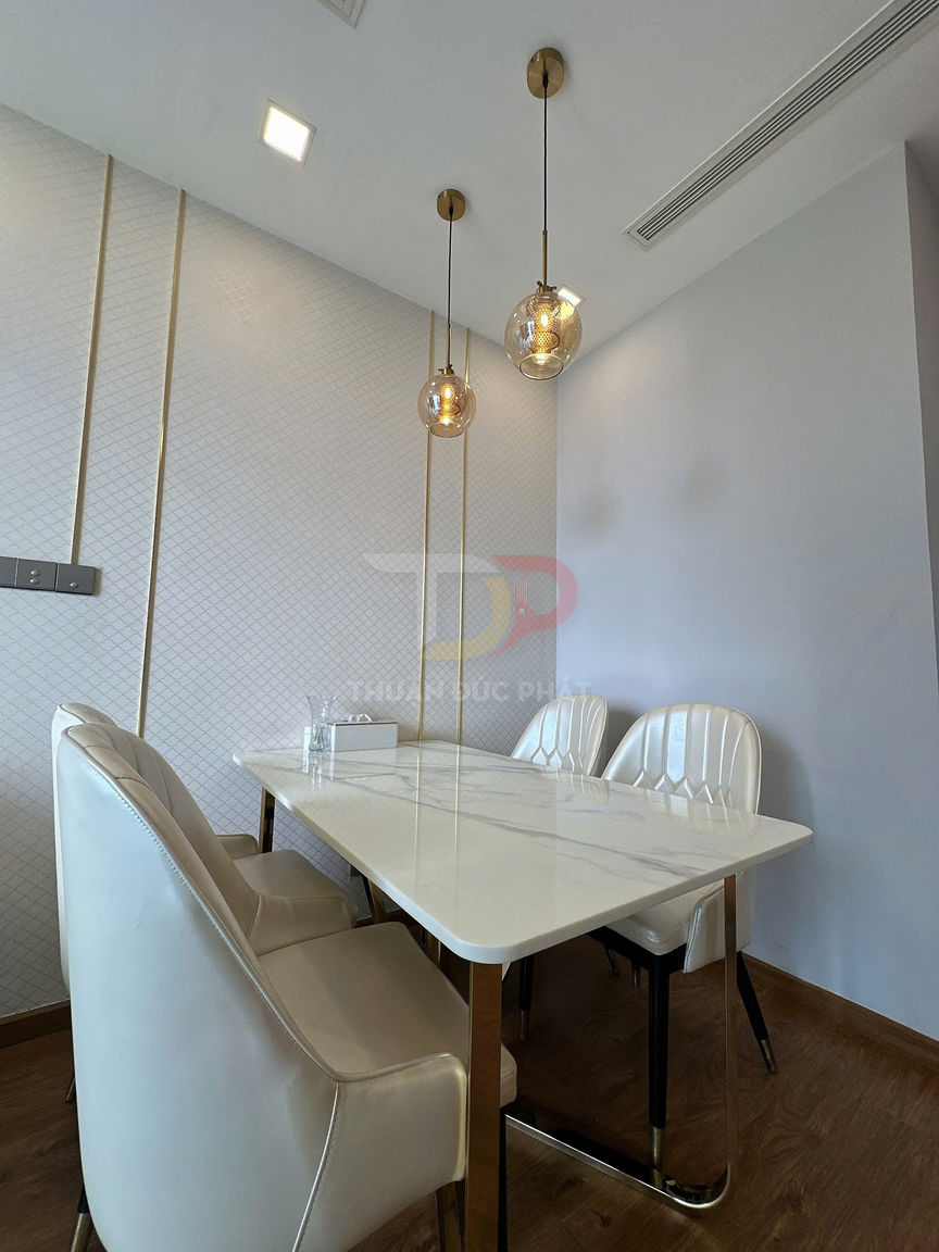 Bộ bàn ăn mặt đá trắng với ghế bọc da màu trắng trong phòng ăn hiện đại có đèn thả trần