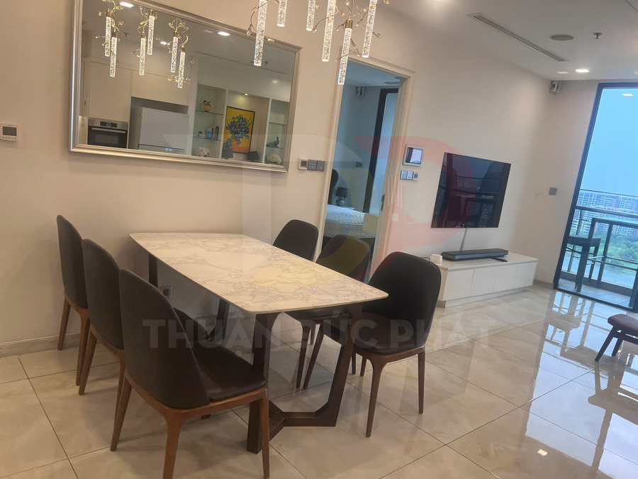 Bộ bàn ăn mặt đá chữ nhật với sáu ghế nệm trong phòng khách căn hộ hiện đại có cửa kính lớn