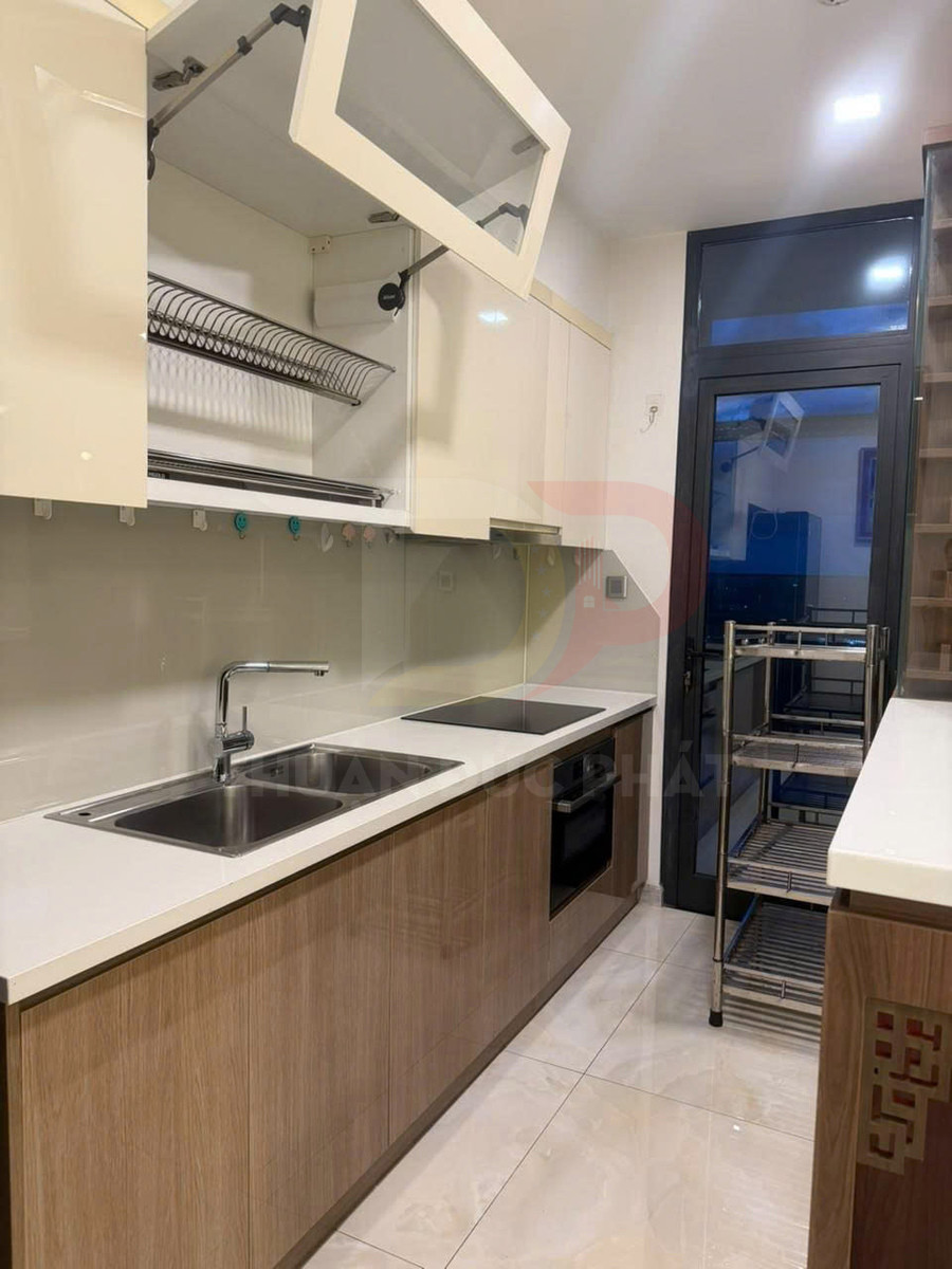 Tủ bếp gỗ hiện đại với bồn rửa inox, bếp từ âm và kệ úp chén inox trong không gian bếp nhỏ gọn