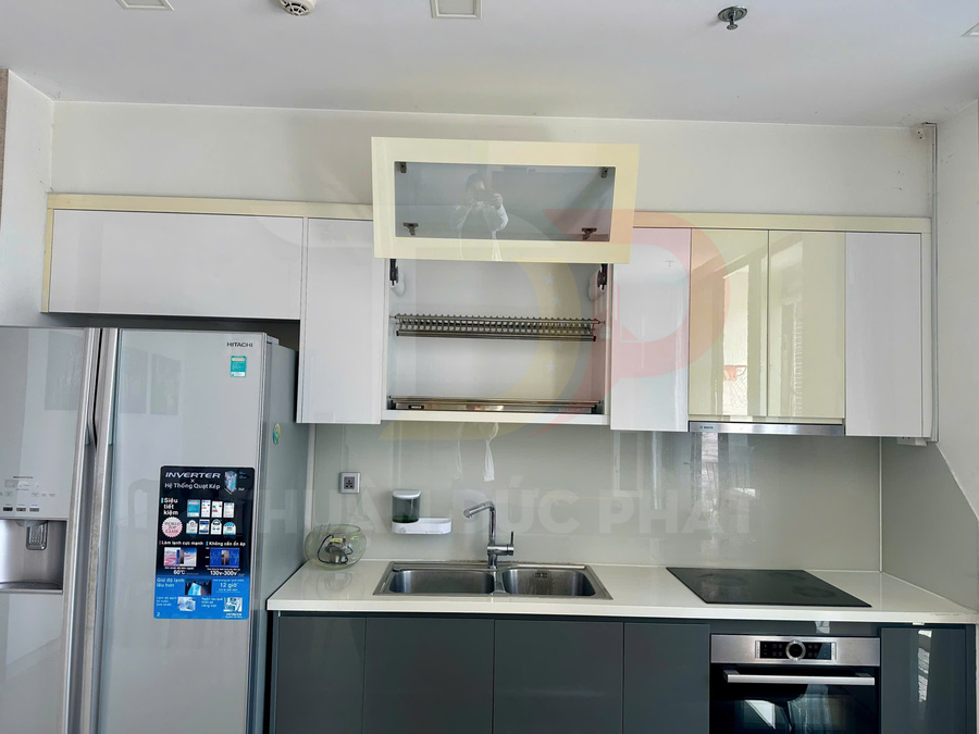 Tủ bếp hiện đại với kệ úp chén inox nâng hạ phía trên bồn rửa đôi trong không gian bếp gọn gàng
