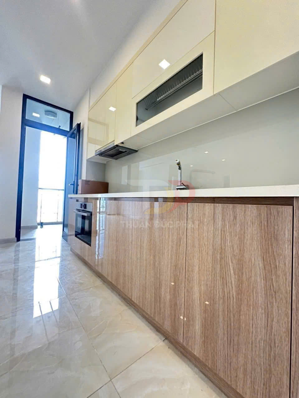 Tủ bếp gỗ hiện đại kèm bếp âm và chậu rửa trong căn hộ sáng sủa