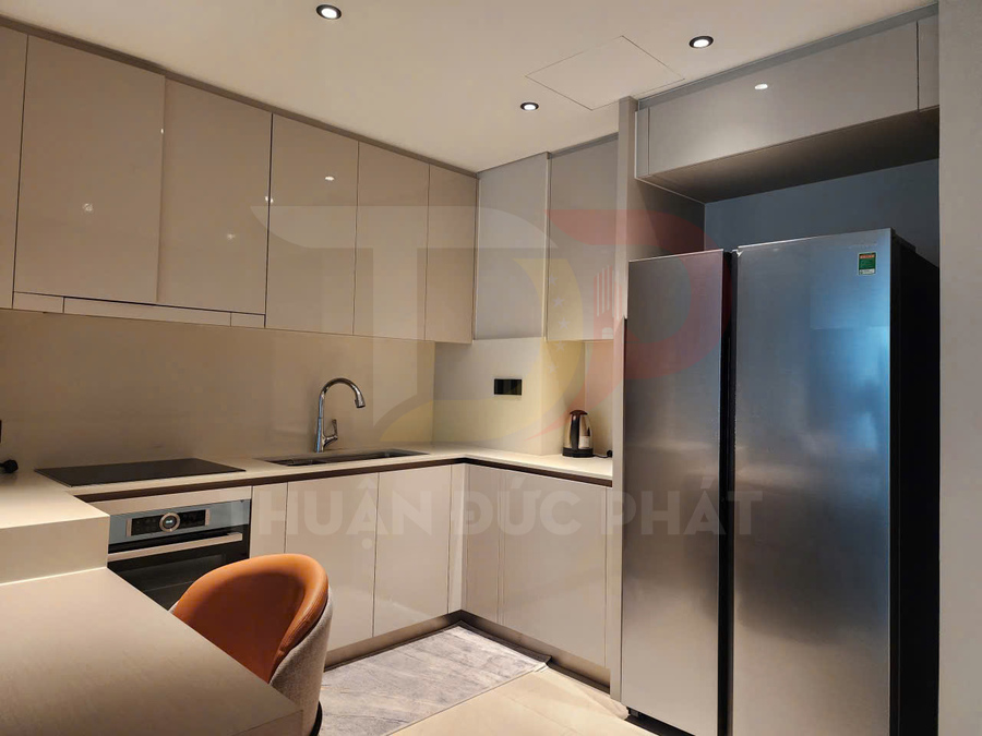 Tủ bếp chữ L hiện đại với tủ lạnh đôi inox, bếp từ âm và chậu rửa inox trong không gian bếp nhỏ gọn