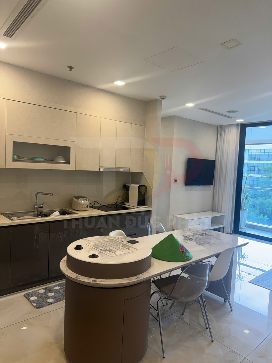 Gian bếp hiện đại với tủ bếp âm tường, bàn đảo đá và bộ bàn ăn nhỏ cạnh cửa kính lớn