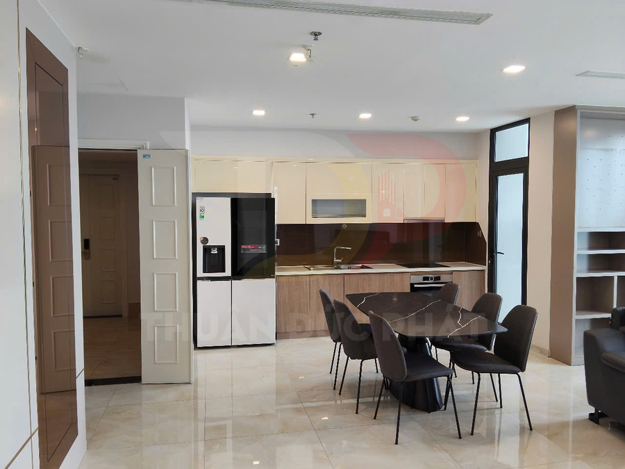 Phòng bếp hiện đại với tủ bếp gỗ, bàn ăn mặt đá đen và tủ lạnh lớn hai cửa màu trắng đen