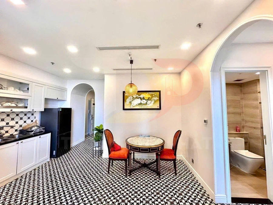 Bàn ăn tròn mặt đá với hai ghế nệm đỏ trong căn bếp lát gạch hoa trắng đen hiện đại