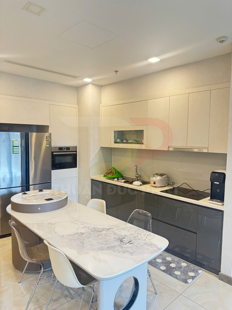 Bếp hiện đại với tủ bếp chữ I, bàn ăn mặt đá, tủ lạnh inox và bếp từ âm kèm máy hút mùi