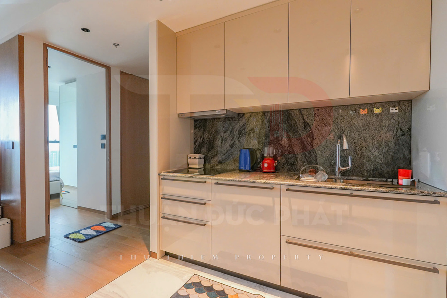 Gian bếp hiện đại với tủ bếp màu kem, mặt đá granite, ấm đun nước điện và máy xay sinh tố đỏ