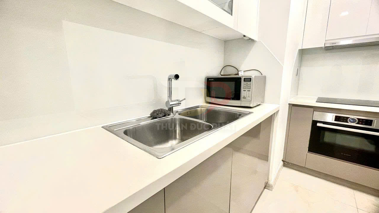 Bồn rửa bát đôi inox với vòi nước hiện đại cạnh lò vi sóng Sharp trong căn bếp nhỏ gọn