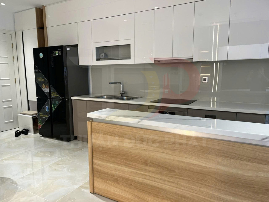 Tủ bếp hiện đại màu trắng kết hợp đảo bếp gỗ, mặt đá sáng cùng tủ lạnh đen trong không gian bếp rộng rãi