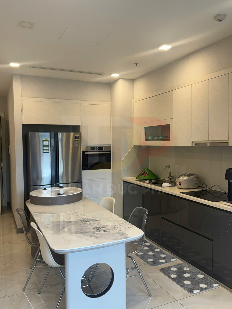 Bếp hiện đại với tủ bếp chữ I, bàn ăn mặt đá và tủ lạnh inox hai cánh sang trọng