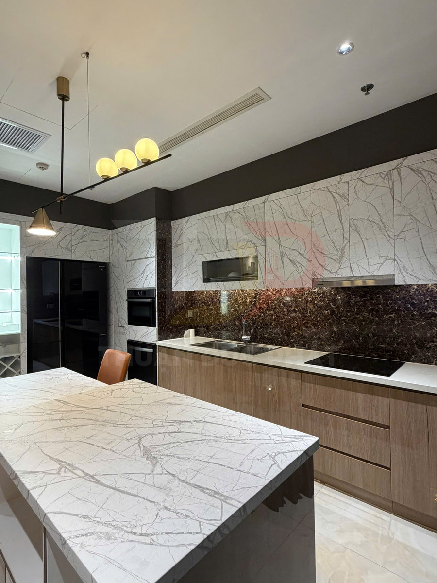 Bếp hiện đại với đảo bếp đá marble trắng vân mây và tủ gỗ, bồn rửa inox cùng bếp từ âm sang trọng