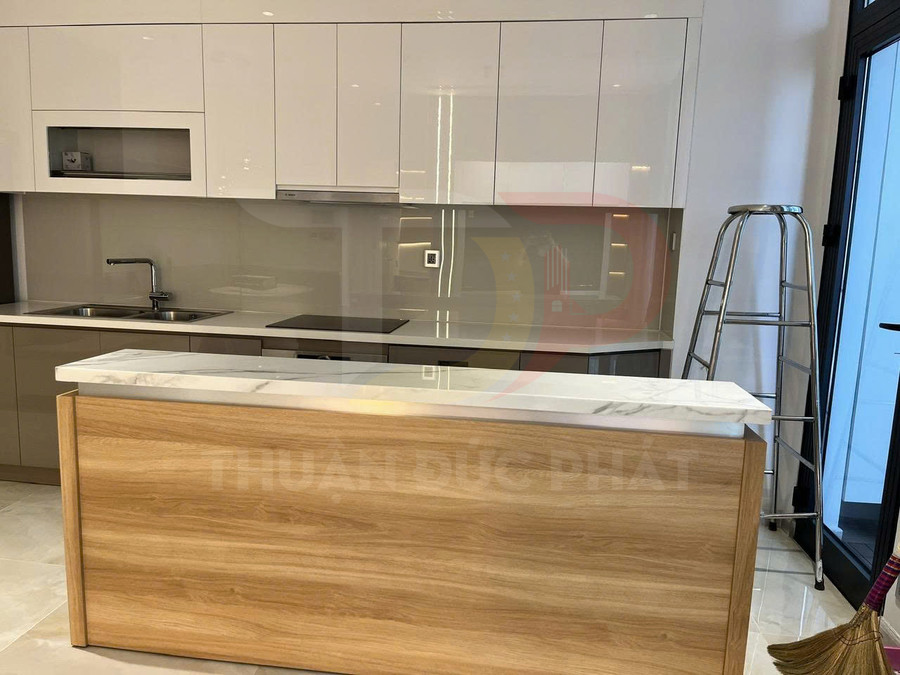 Tủ bếp gỗ công nghiệp hiện đại màu trắng kết hợp đảo bếp mặt đá trong không gian bếp sáng