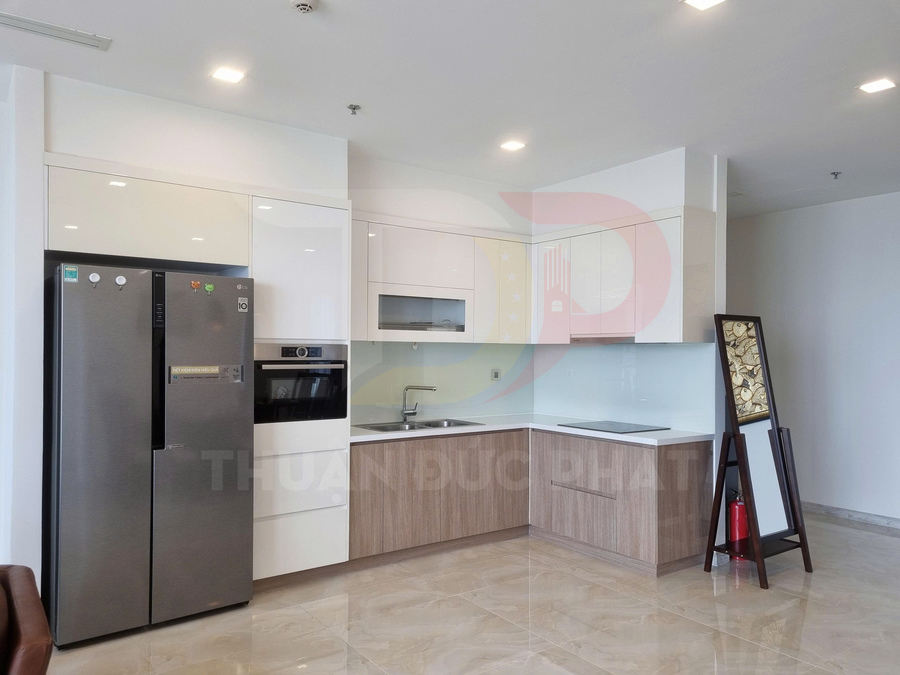 Tủ bếp chữ L hiện đại với tủ lạnh LG hai cánh, bếp âm và chậu rửa inox trong căn hộ sáng sủa