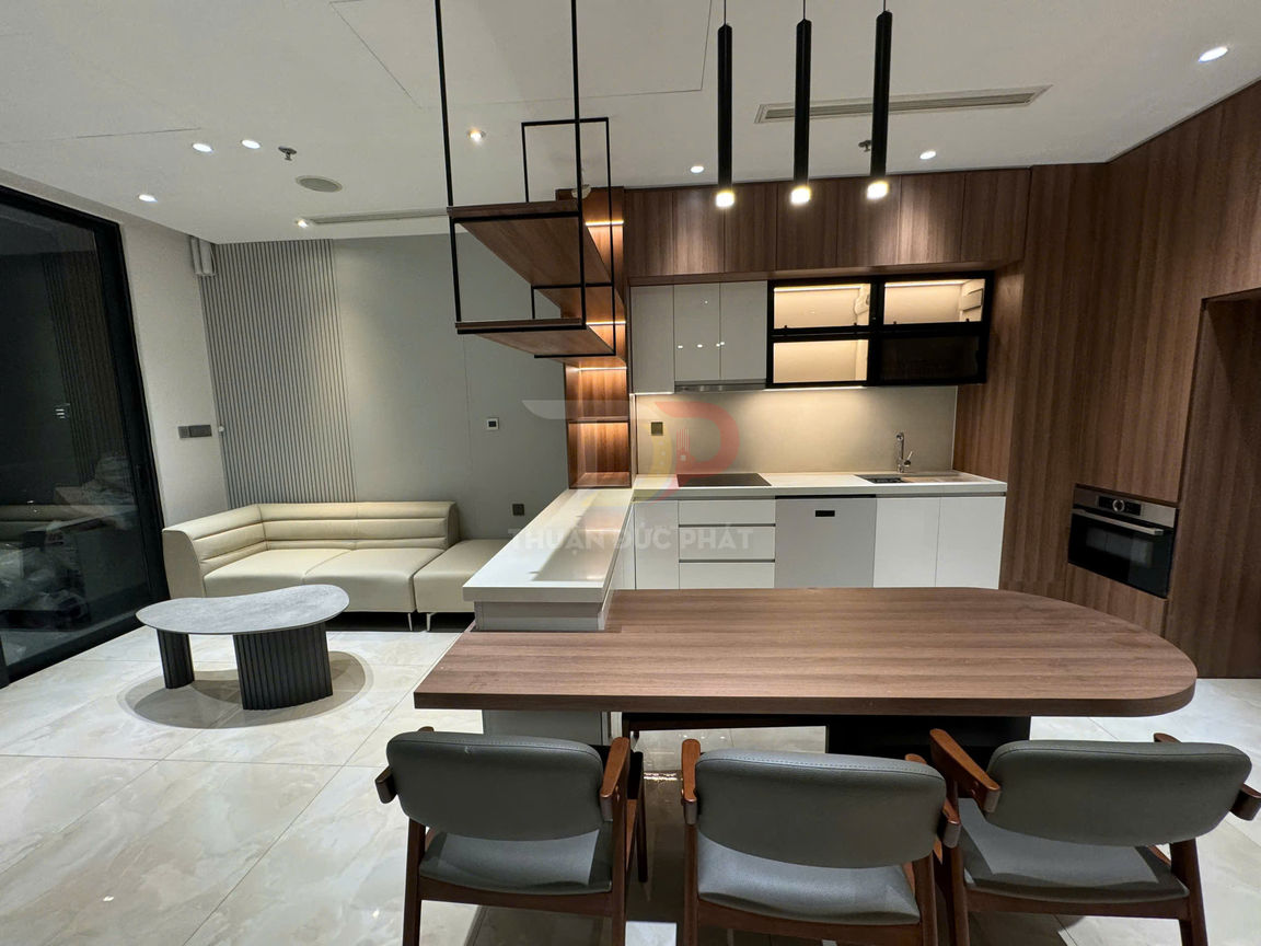 Phòng bếp và phòng khách hiện đại với tủ bếp gỗ, bàn ăn gỗ, sofa chữ L và bàn trà tròn