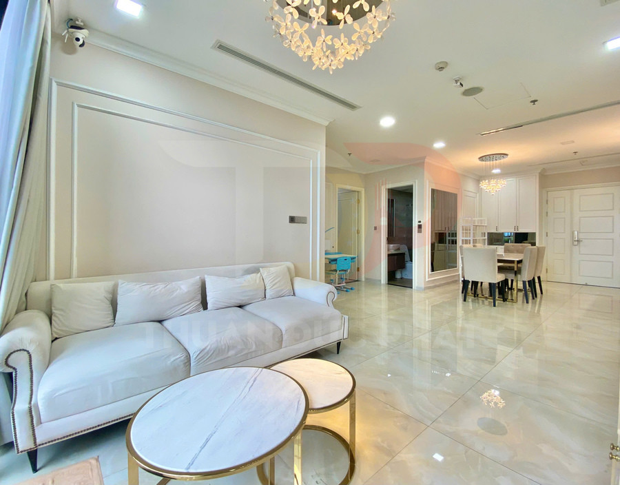 Phòng khách căn hộ cao cấp với sofa trắng, bàn trà tròn mặt đá và khu bàn ăn hiện đại liền kề