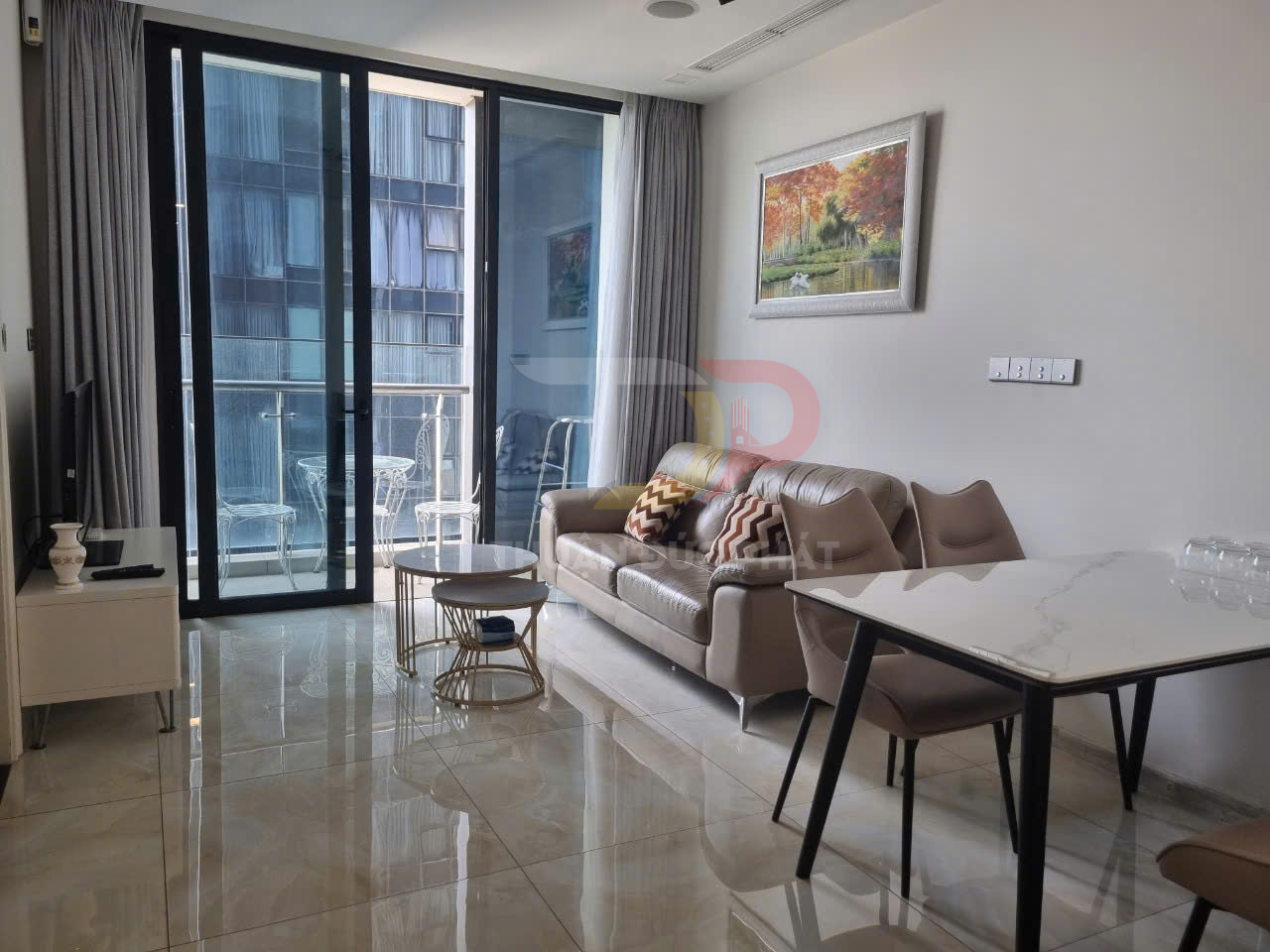 Phòng khách chung cư hiện đại với sofa da, bàn trà tròn, bàn ăn mặt đá và cửa kính lớn nhìn ra ban công