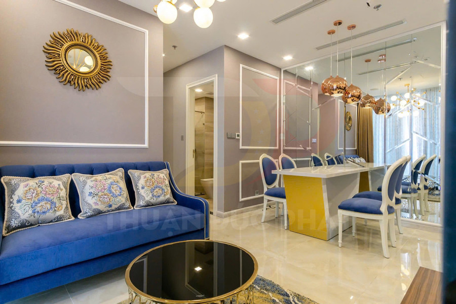Phòng khách và bàn ăn chung cư hiện đại với sofa xanh, bàn trà tròn và ghế ăn bọc nệm xanh sang trọng