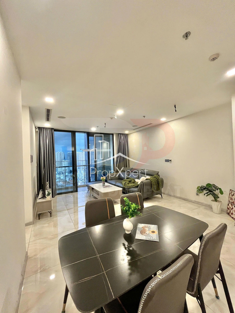 Phòng khách căn hộ hiện đại với bộ sofa xám, bàn trà, bàn ăn đen và cửa kính lớn nhìn ra thành phố