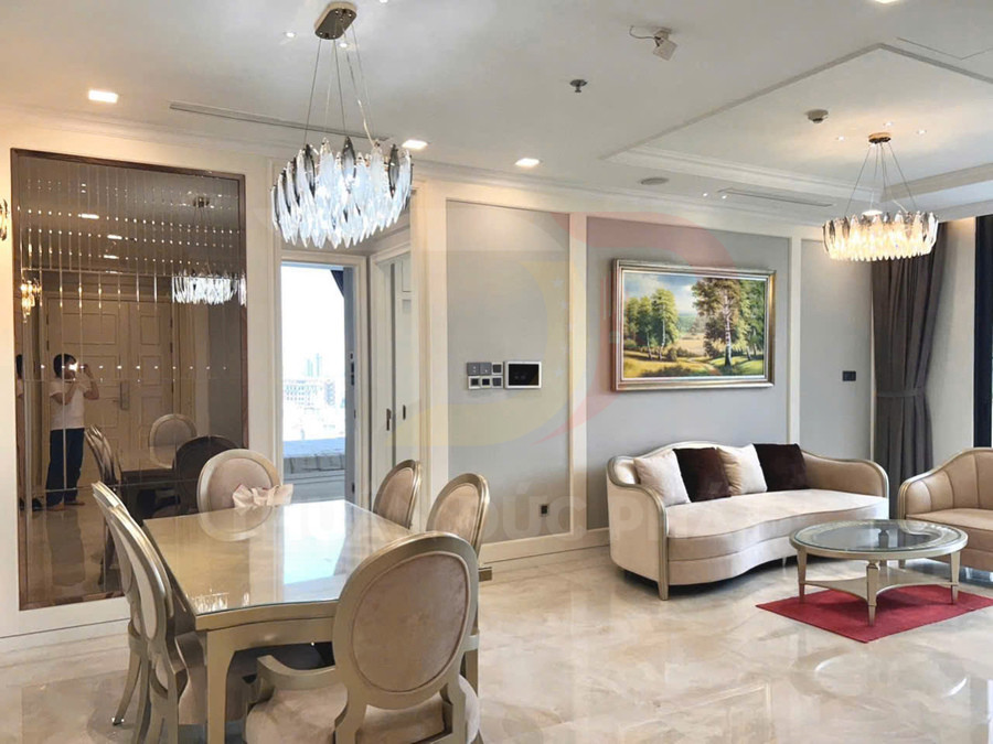 Phòng khách chung cư cao cấp với sofa màu kem, bàn kính tròn và bộ bàn ăn sang trọng cạnh đèn chùm