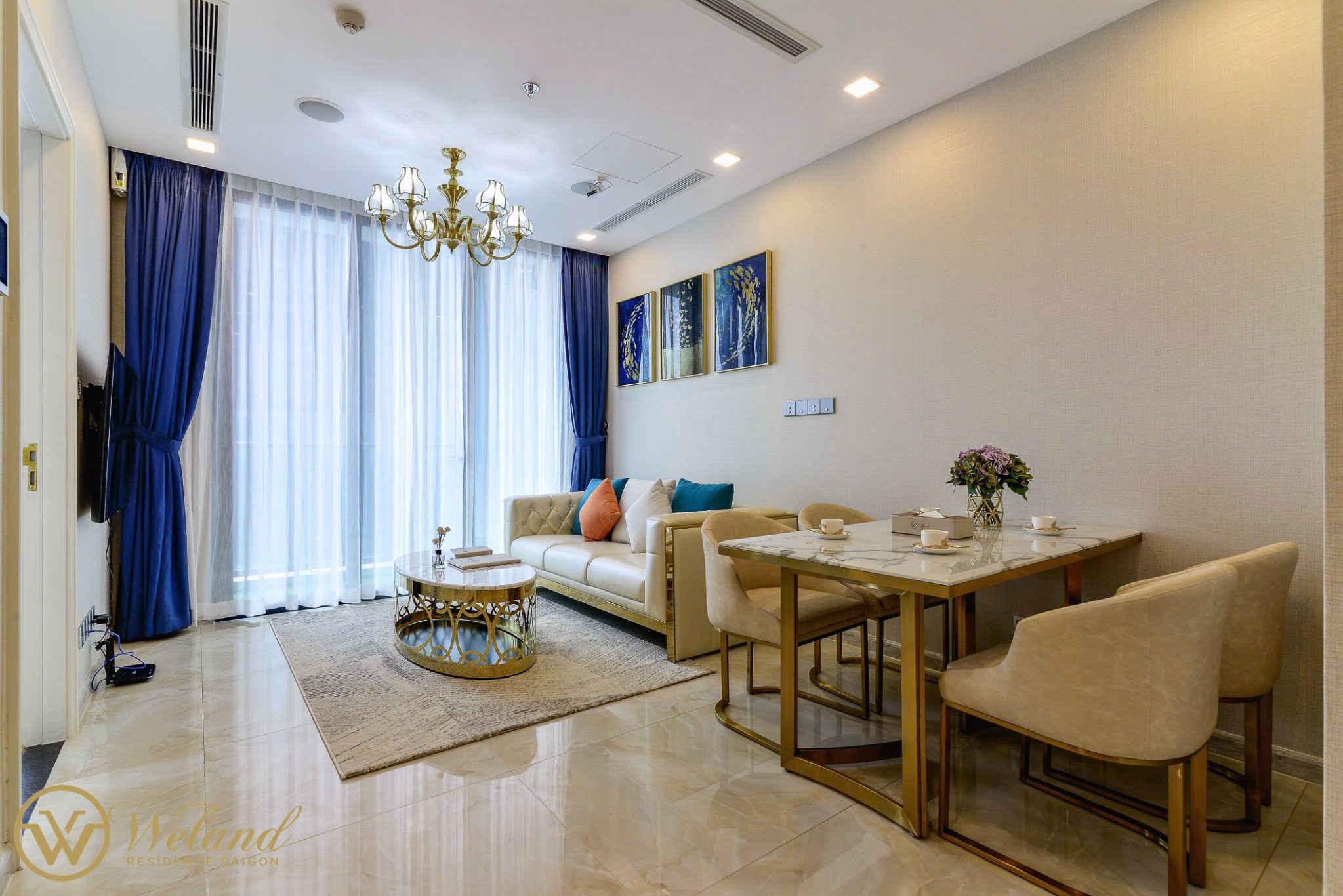 Phòng khách chung cư cao cấp với sofa kem, bàn trà tròn mạ vàng và bộ bàn ăn đá sang trọng