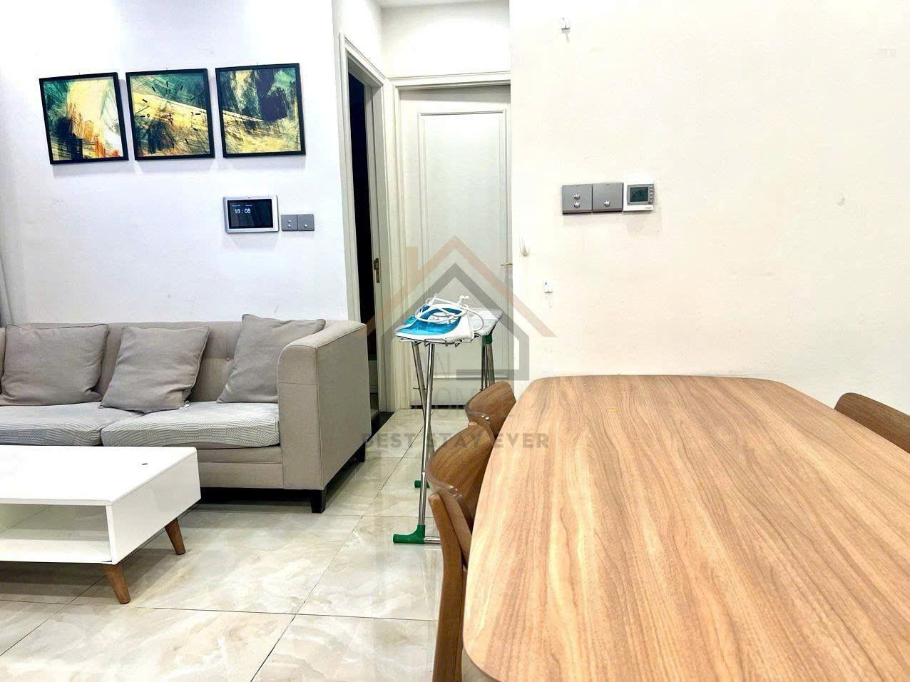 Bàn ăn gỗ cạnh sofa vải màu be trong phòng khách chung cư hiện đại