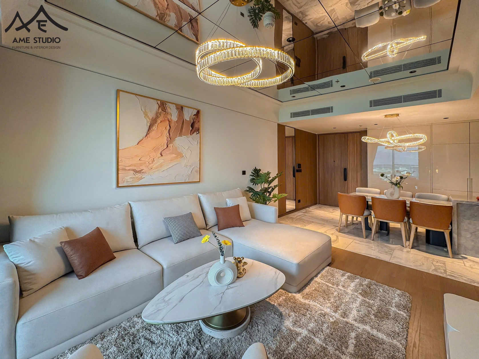 Phòng khách hiện đại với sofa góc bọc nỉ màu kem, bàn trà mặt đá và đèn trần trang trí sang trọng