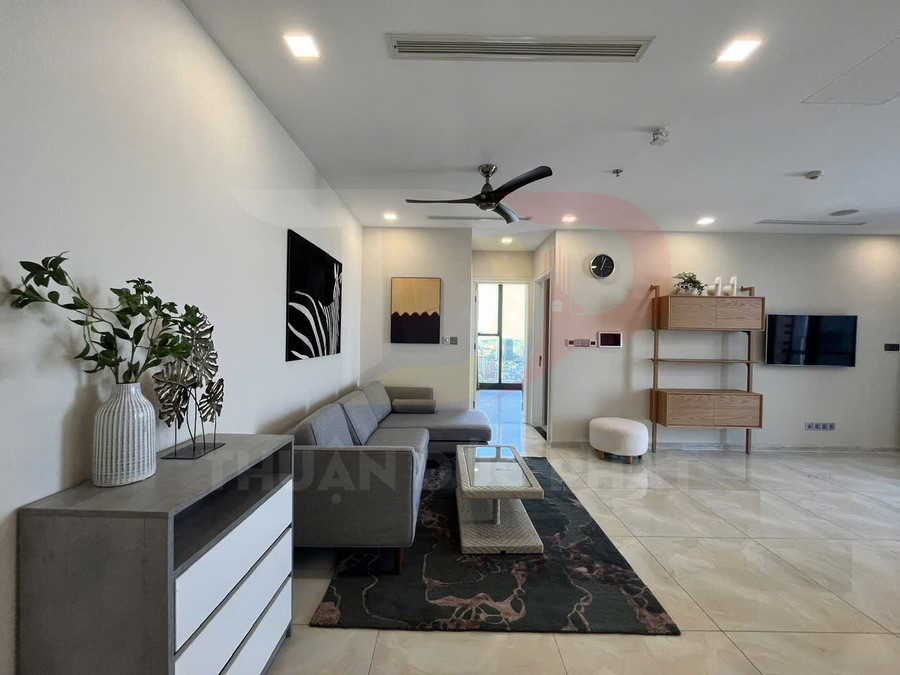 Phòng khách chung cư hiện đại với sofa xám, bàn trà kính, kệ gỗ treo tường và tivi gắn tường