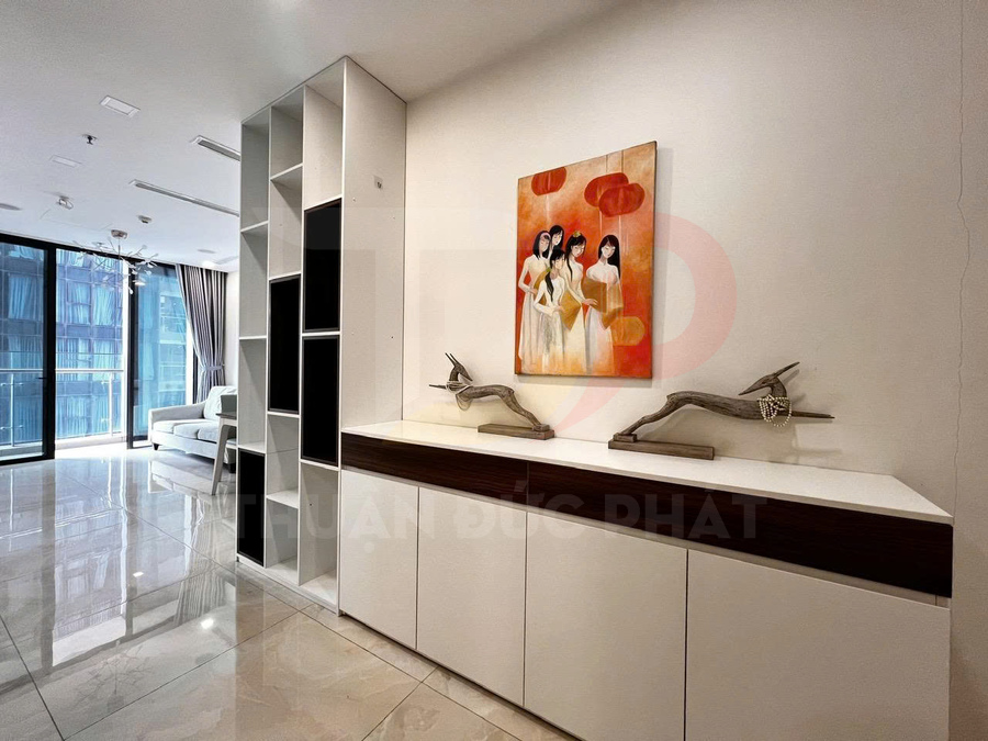 Tủ trang trí phòng khách hiện đại màu trắng với tranh treo tường và đồ decor gỗ trên mặt tủ
