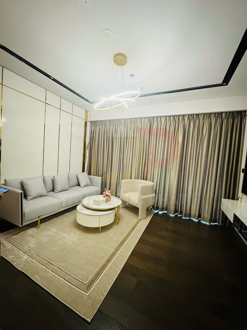 Phòng khách hiện đại với sofa xám, ghế bành, bàn trà tròn trắng và đèn trần trang trí sang trọng