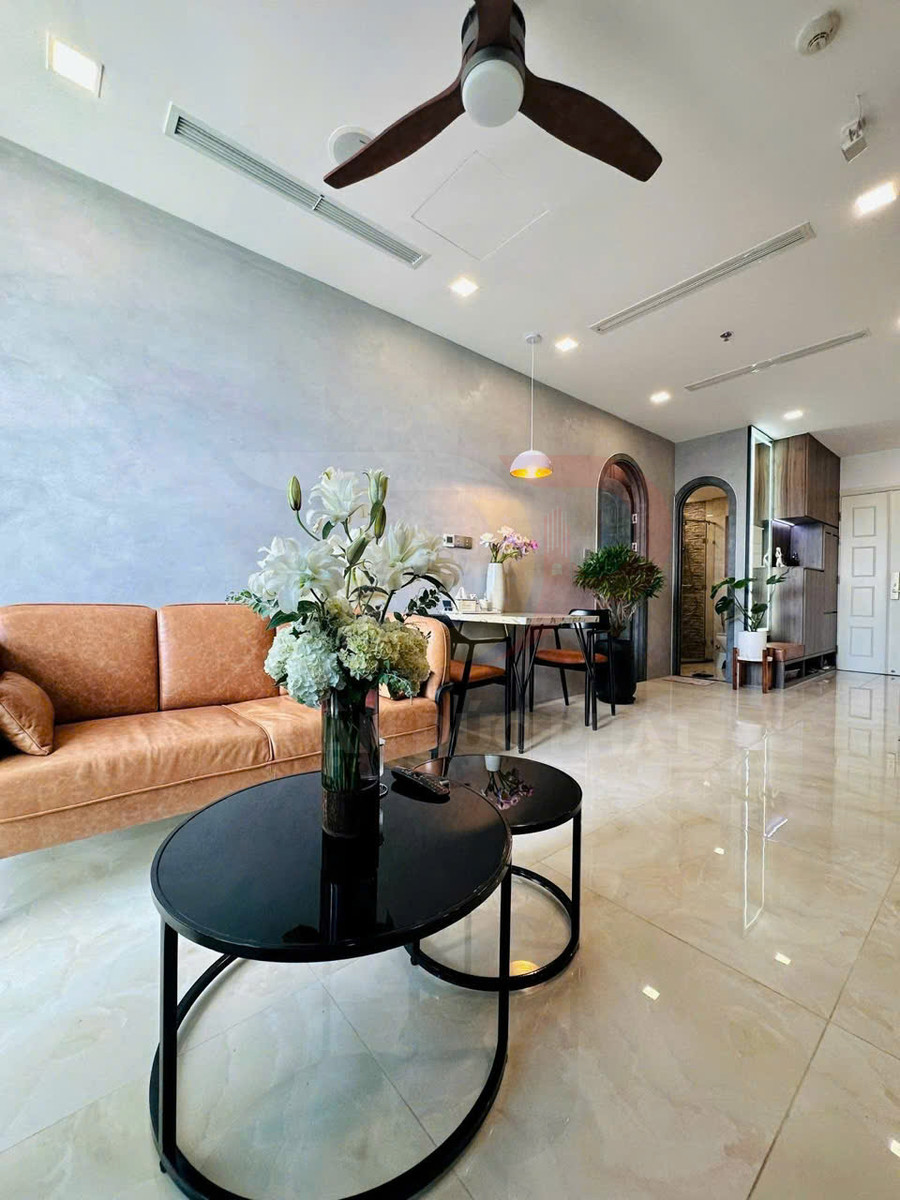 Bàn trà mặt kính đen tròn đặt bình hoa trong phòng khách hiện đại với sofa da và trần quạt trần gỗ