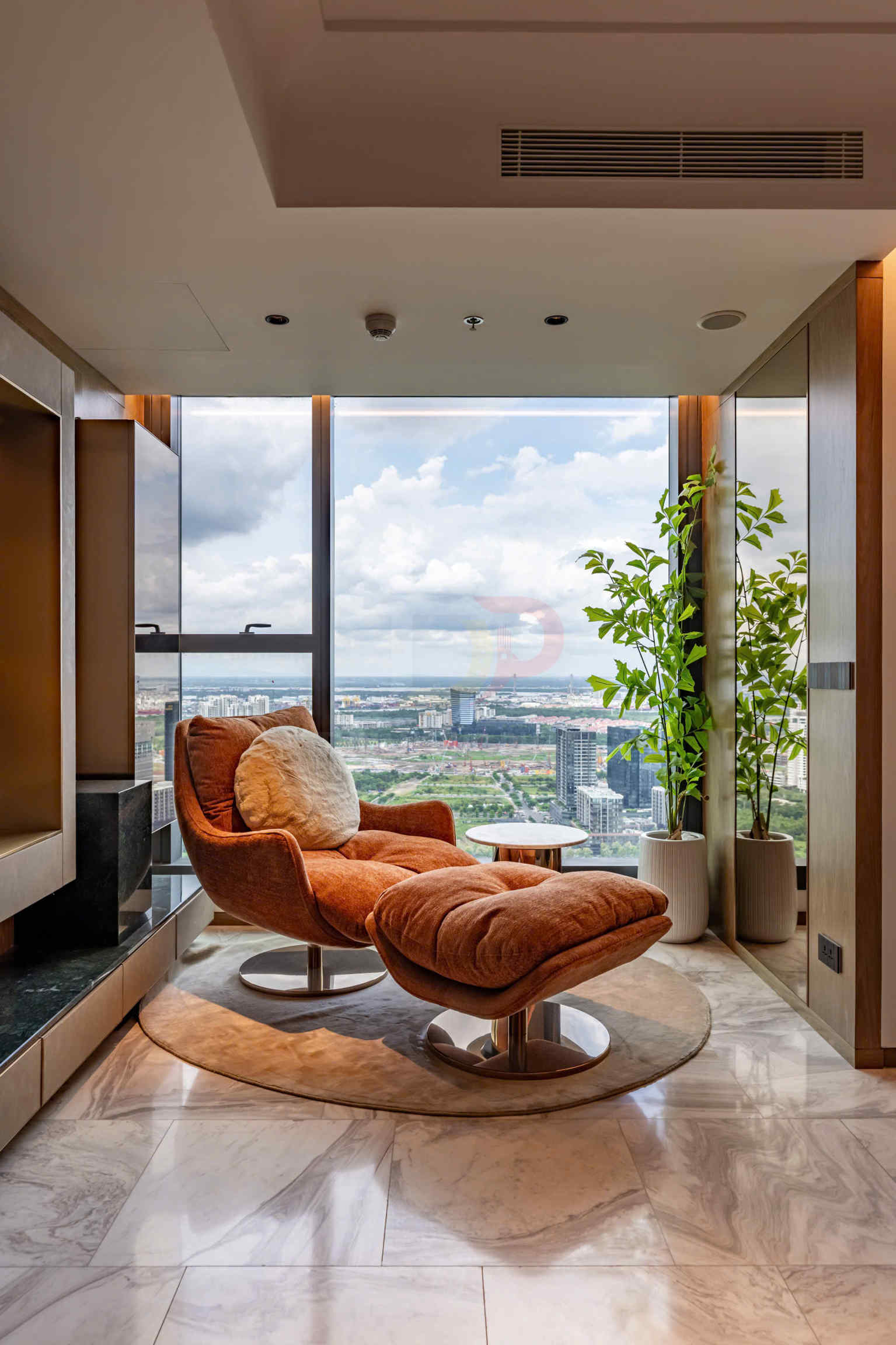 Ghế thư giãn bọc nỉ màu cam với đôn chân đặt cạnh cửa sổ kính lớn view thành phố