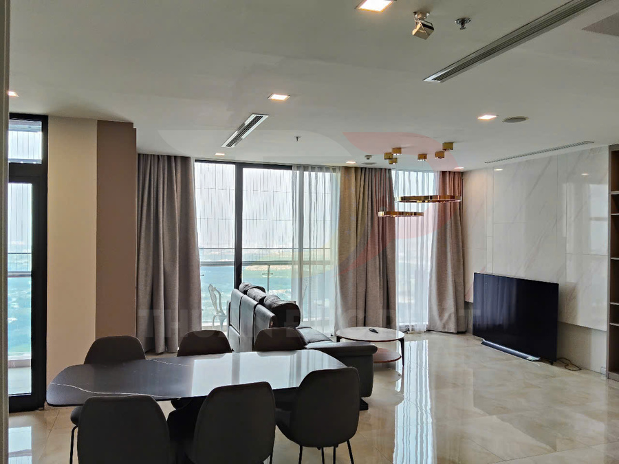 Phòng khách chung cư cao cấp với sofa da, bàn ăn hiện đại và tivi màn hình phẳng cạnh cửa sổ lớn nhìn ra biển